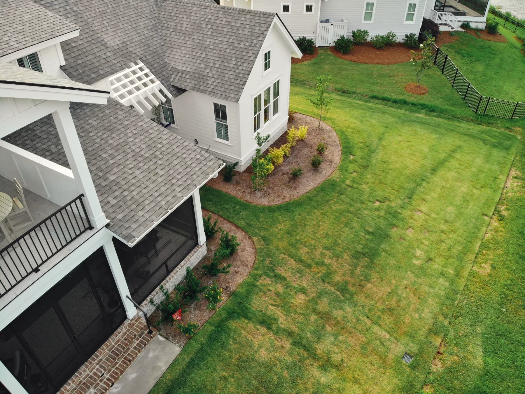 Before: aerial view of the landscaped Hampton Hall backyard with lawn but no hard surface for seating near the water
