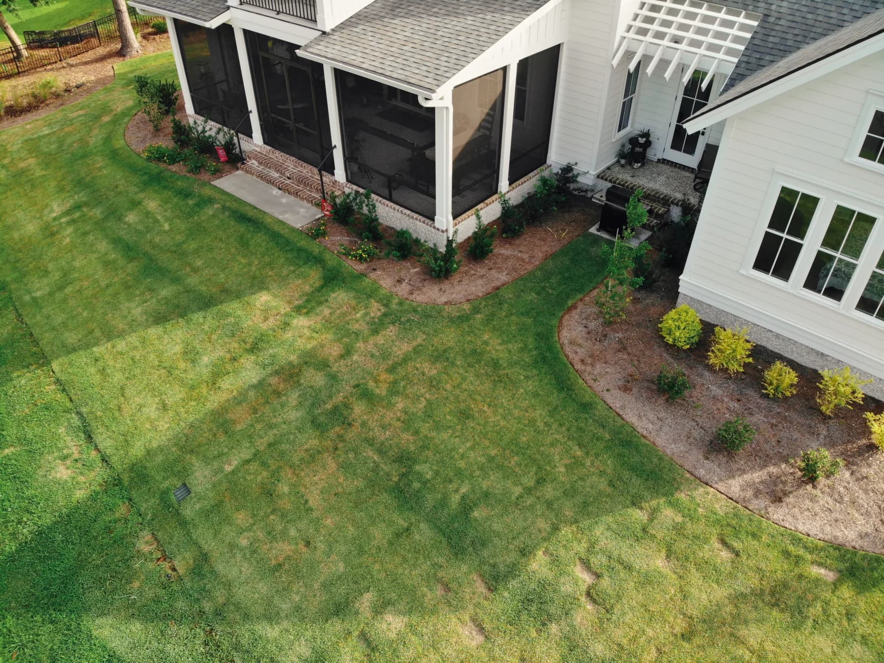 Before: curved landscape beds framing an open lawn without a patio or outdoor gathering area