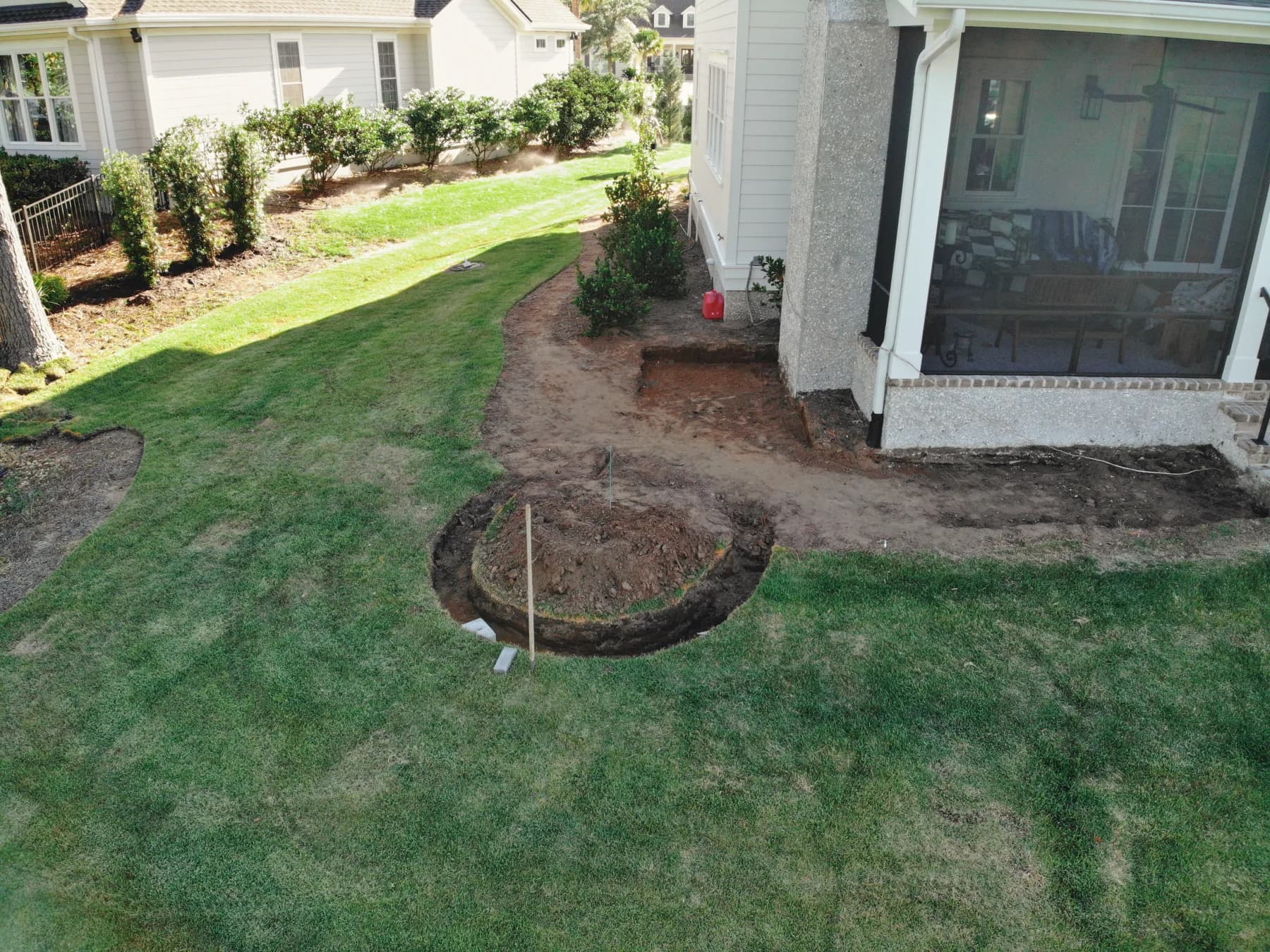 Construction progress showing the prepared patio footprint beside the screened porch and rear entry