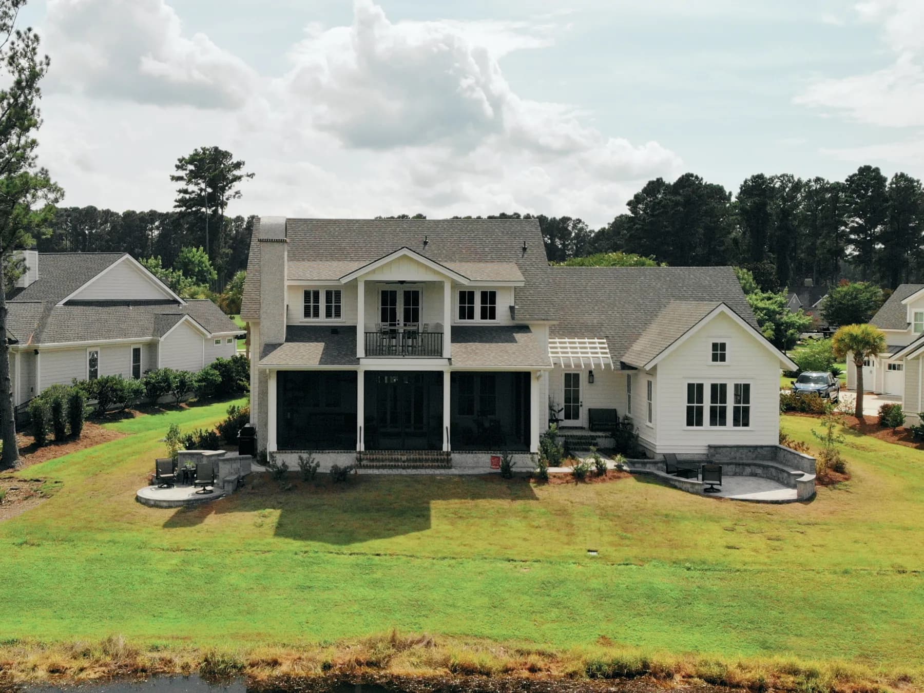 Wide waterfront view of the completed paver patio, grill area, and curved sitting wall