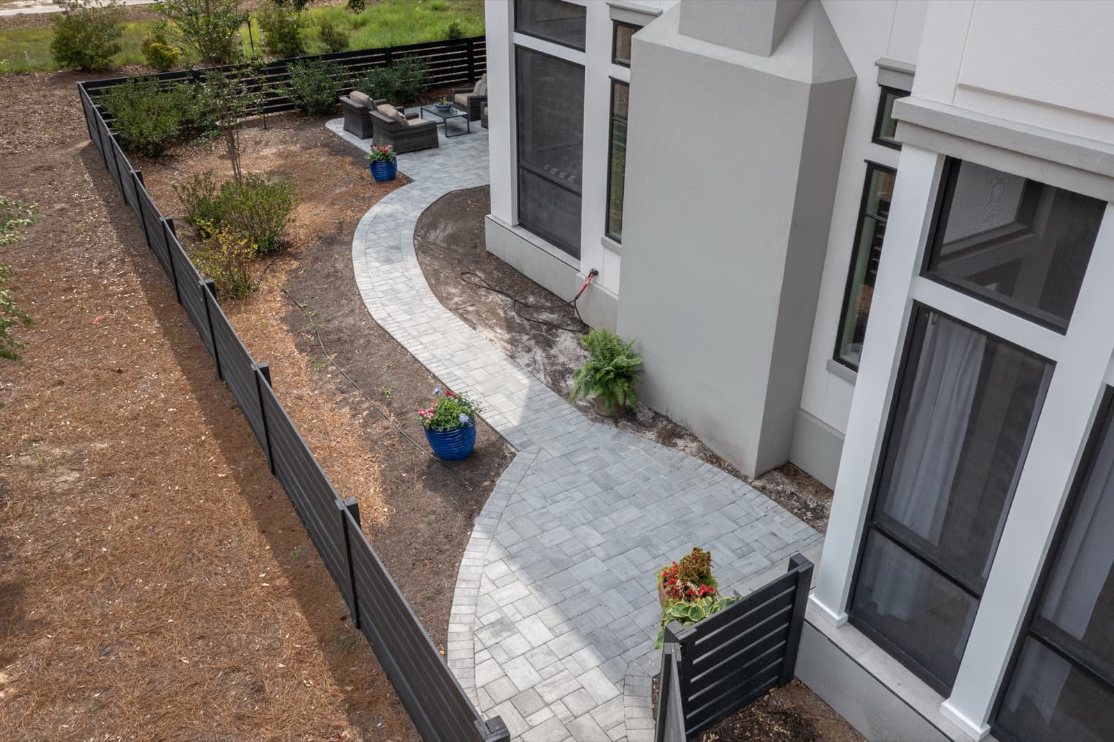 Winding light-grey paver path running alongside the contemporary coastal home