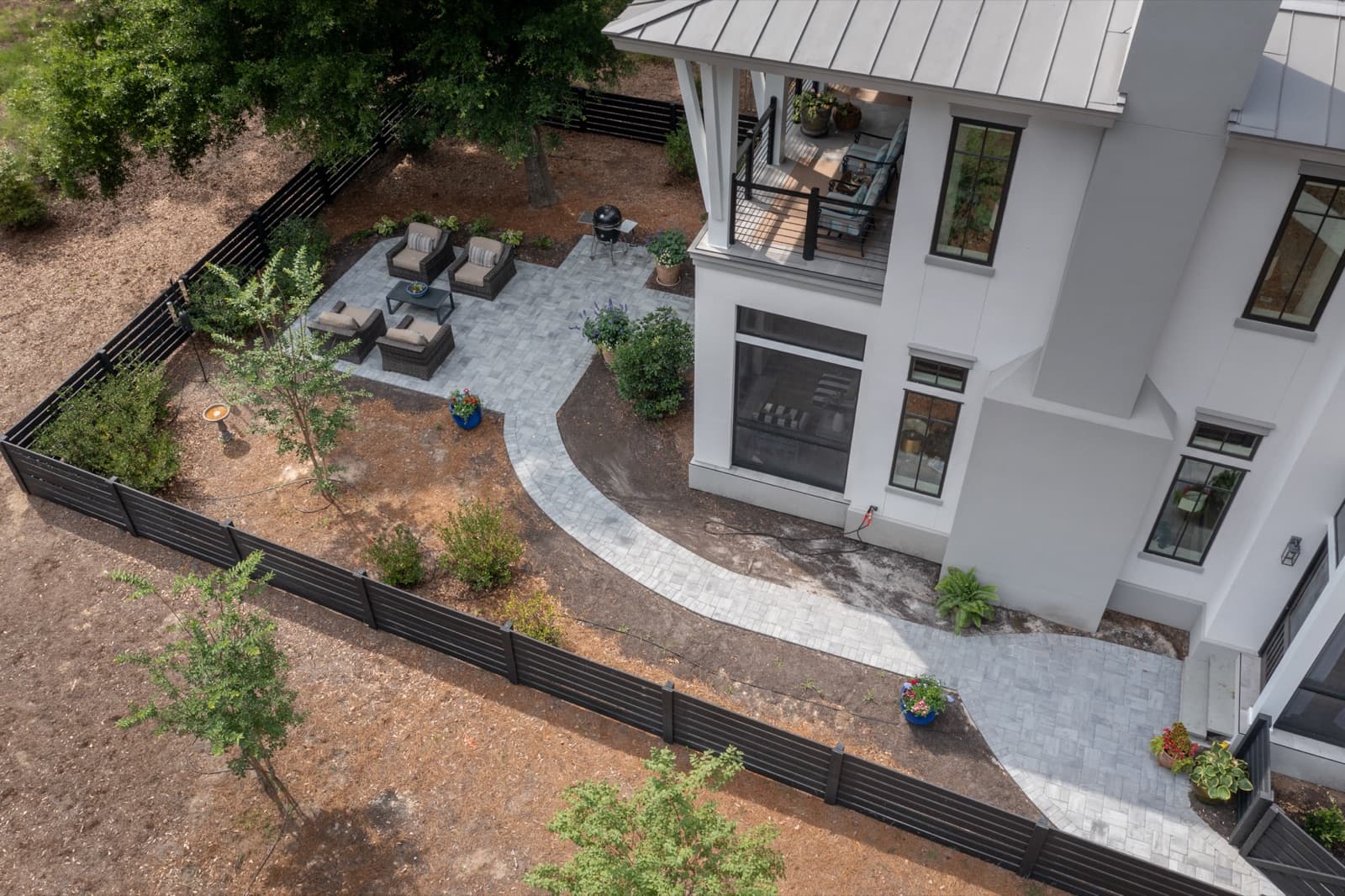 The finished paver patio and path against the metal-roofed contemporary home