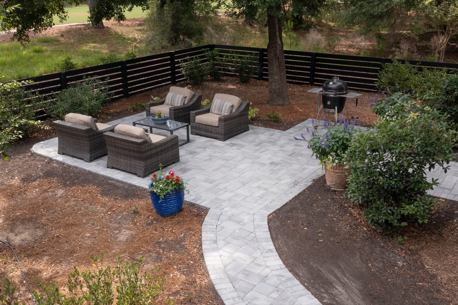 Wide view of the Cat Island outdoor living space with privacy fence and plantings