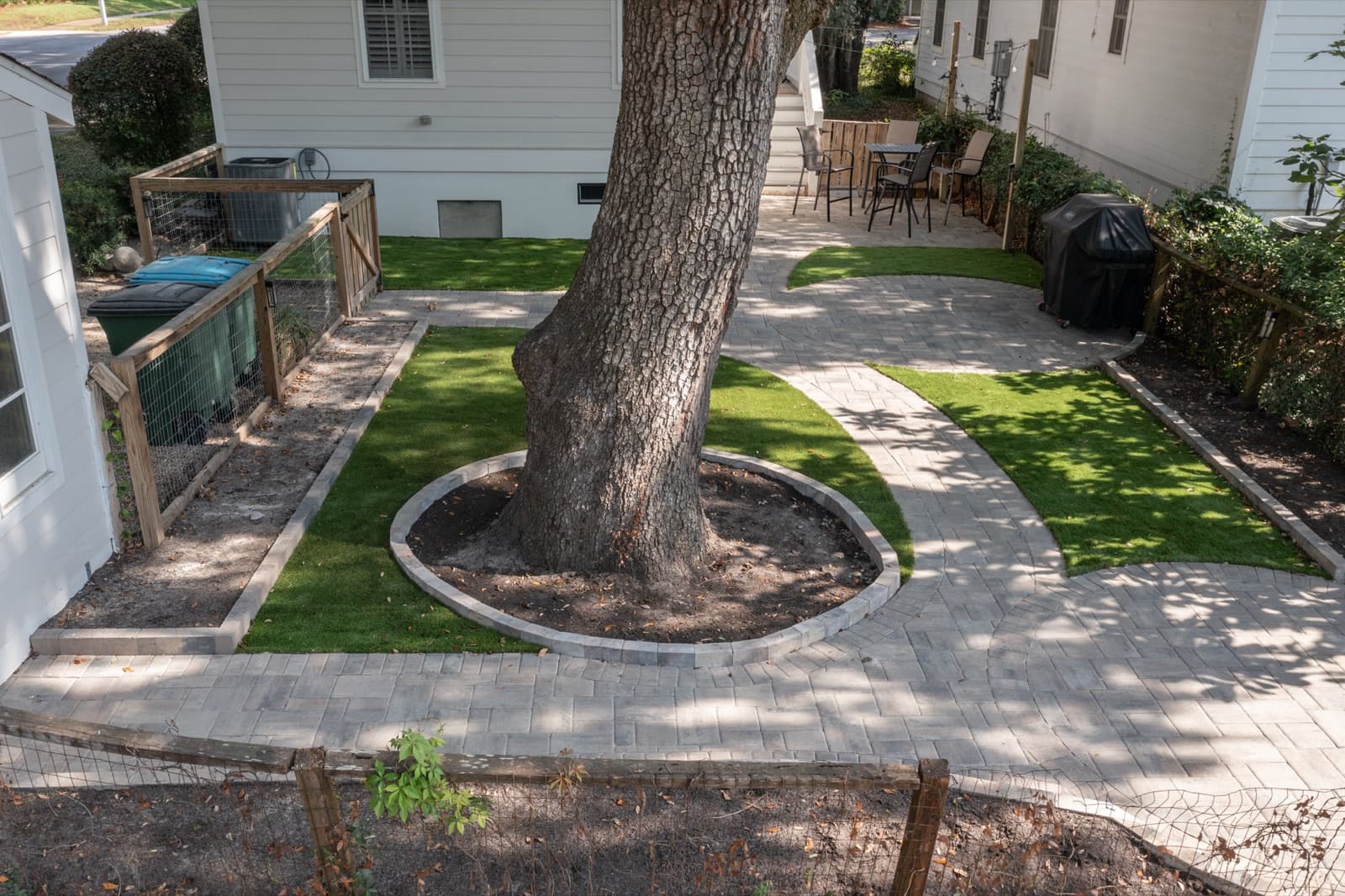 Artificial turf and paver patio woven around a heritage live oak with a circular paver tree-ring in a Beaufort, SC backyard