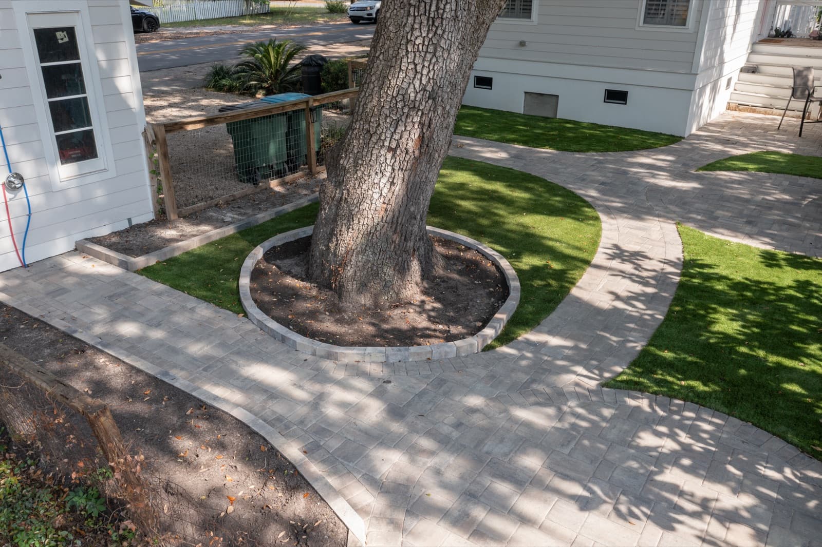 Artificial turf panels and paver walkways flowing around a live oak with a circular paver tree-ring