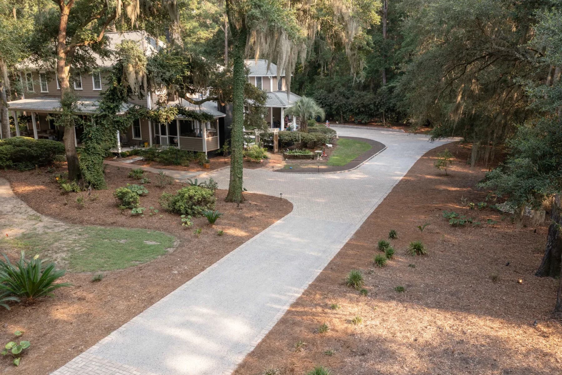 Long paver driveway approaching a Lowcountry home beneath mature live oaks on James Island