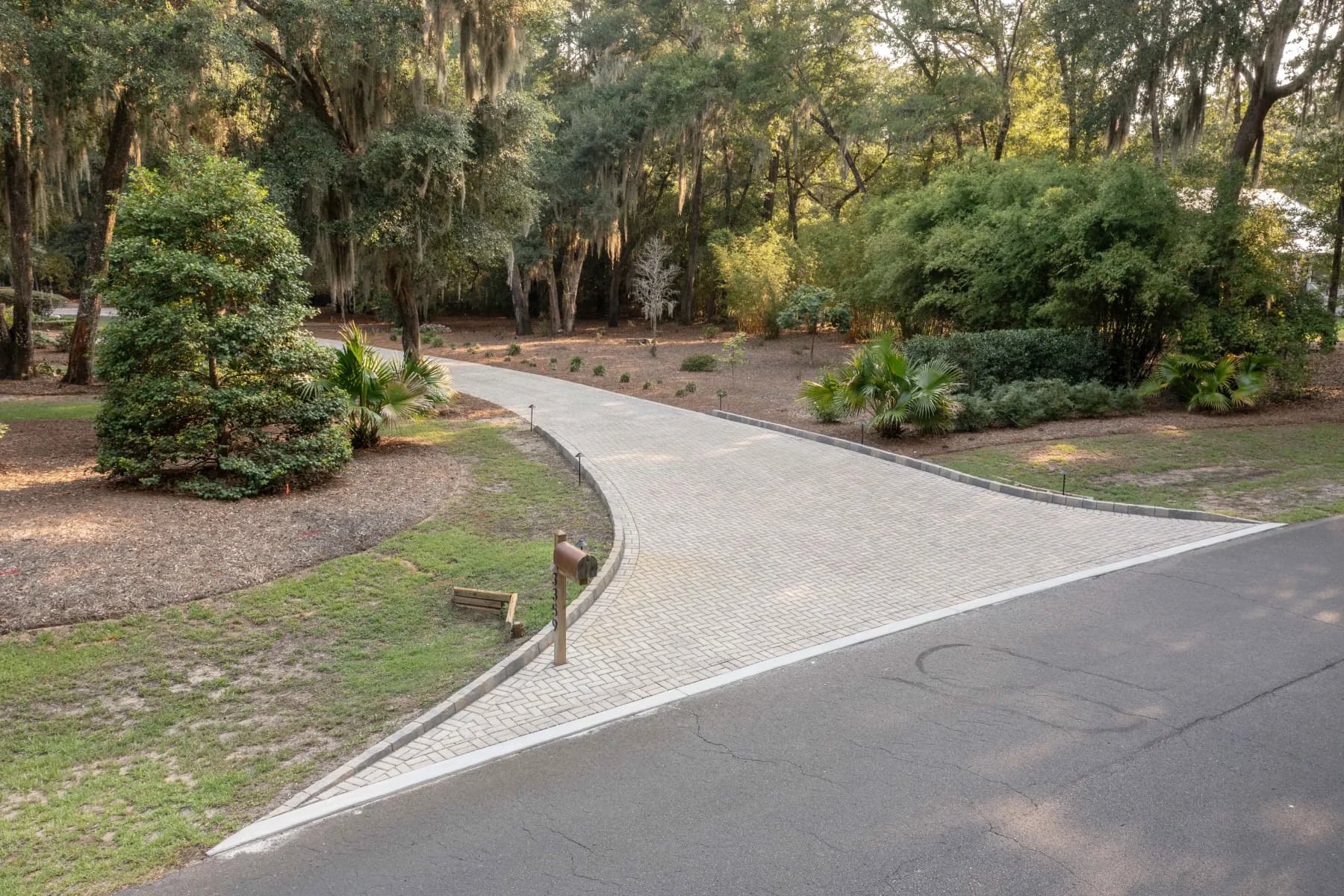 Finished paver driveway entrance curving into a wooded residential property on James Island