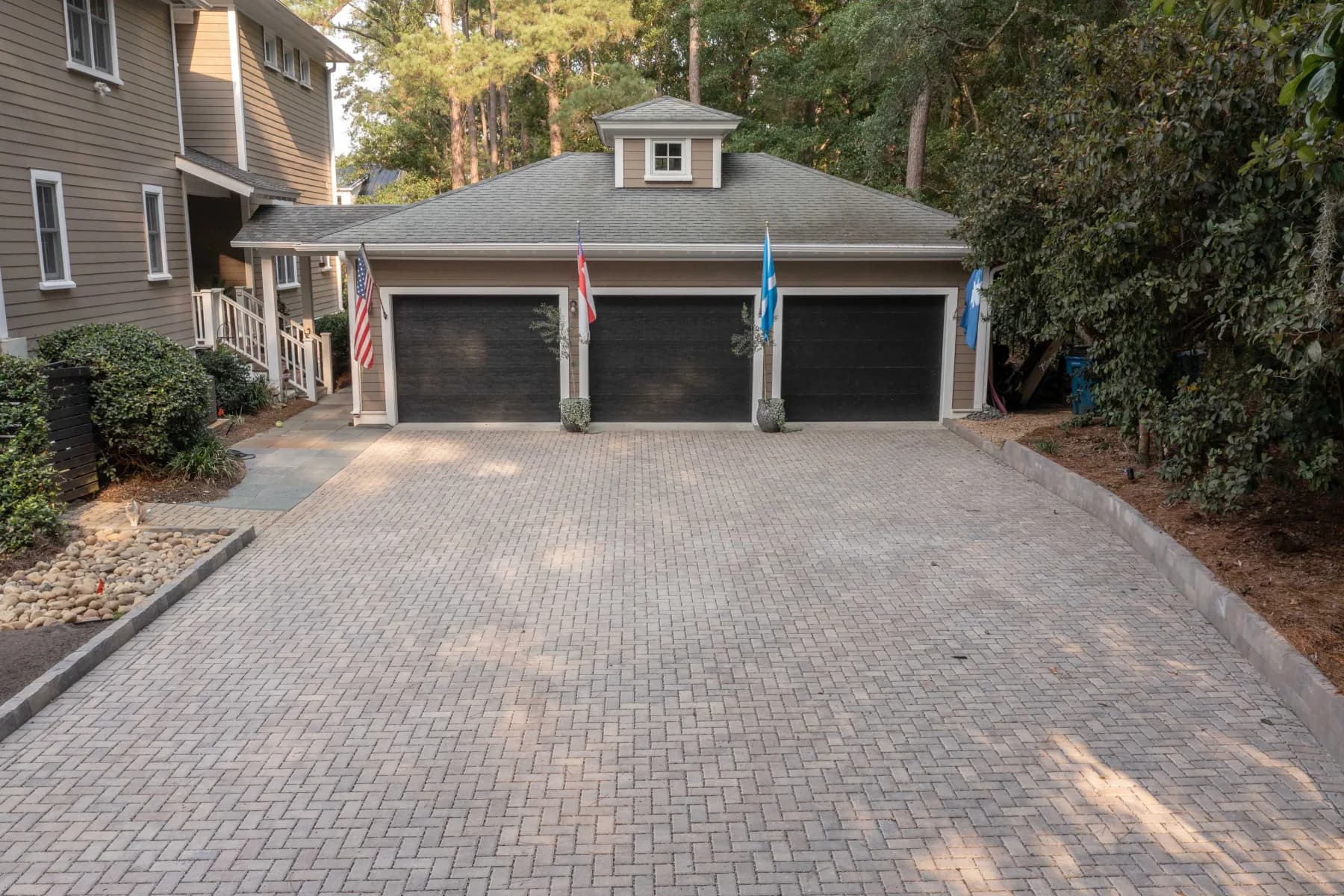 Paver driveway apron providing a broad finished approach to the home’s three-car garage