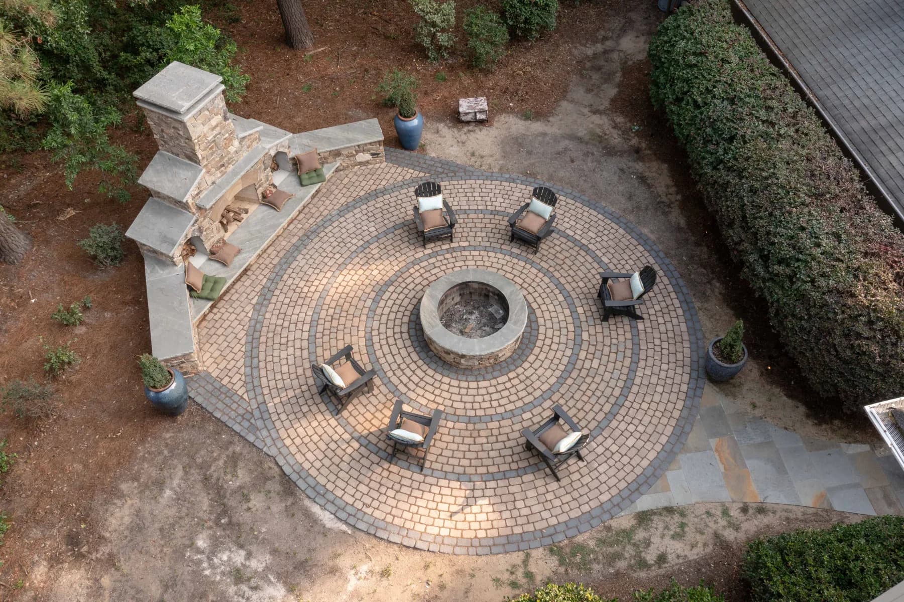 Aerial view showing the concentric paver bands around the fire pit and the stone fireplace seating area